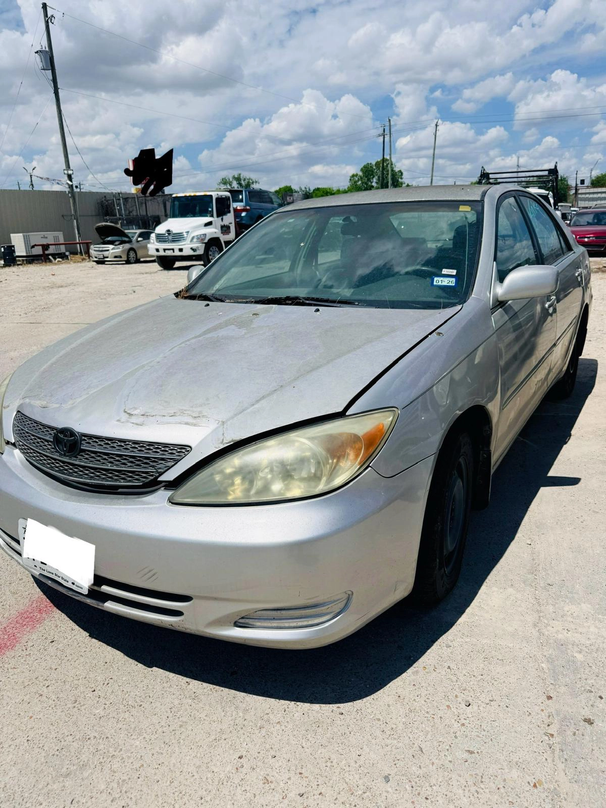 Damaged Toyota Camry in Houston ready to be sold for cash as a junk car with visible wear and front-end issues